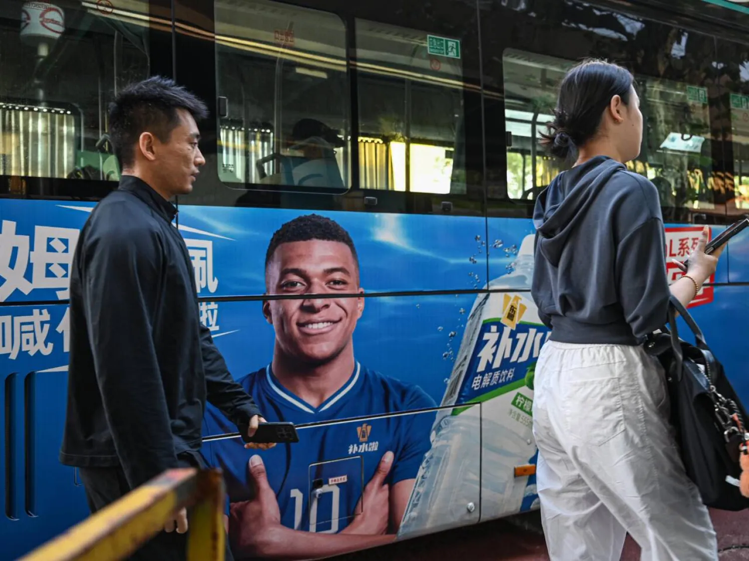 People walk past a bus featuring French football star Kylian Mbappe. Jade GAO / AFP
