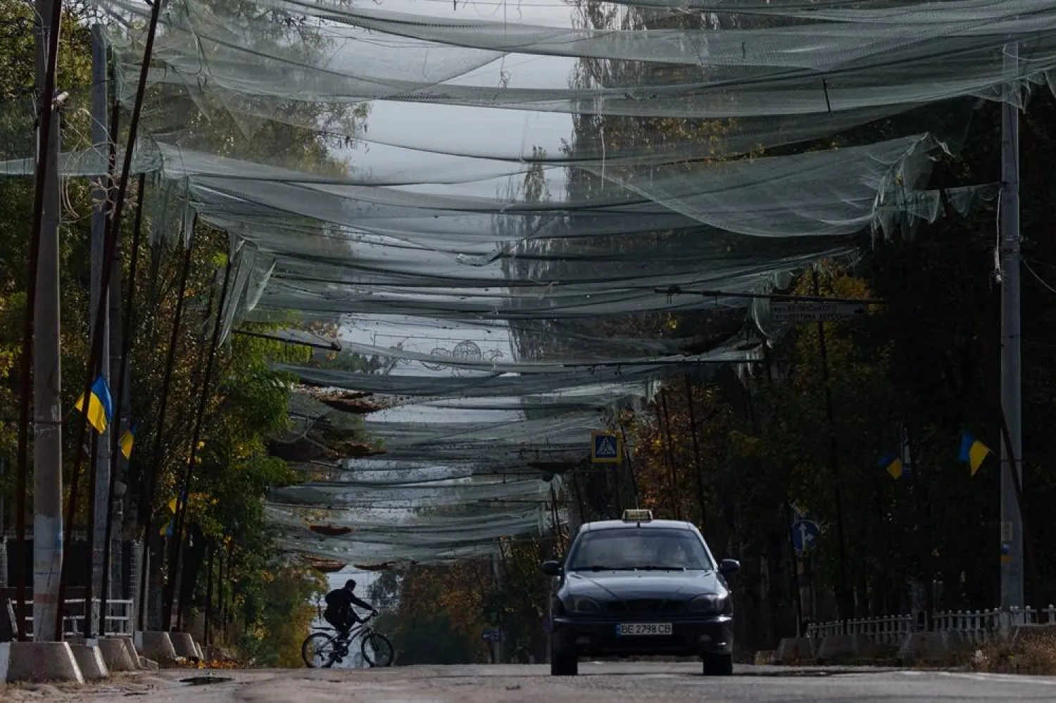 A local man rides a bicycle beneath anti-drone nets stretched over a street during a local ceasefire related to a humanitarian aid mission in Oleshky, in Kherson, Ukraine, Wednesday, Oct. 28, 2026. (AP)