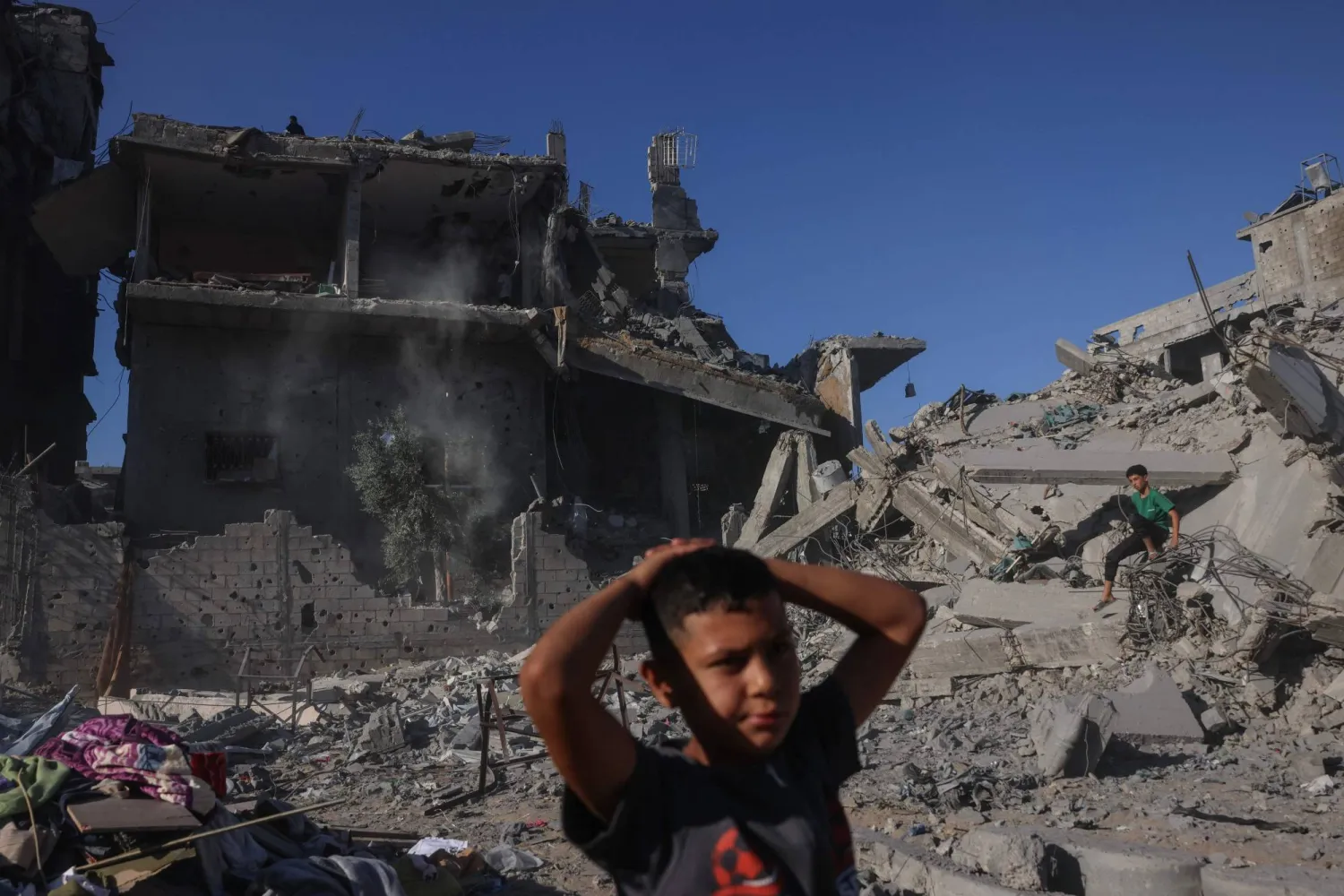 صبيان فلسطينيان وسط الدمار بعد استهداف مبنى بغارة إسرائيلية غرب جباليا شمال قطاع غزة الجمعة (أ.ف.ب)