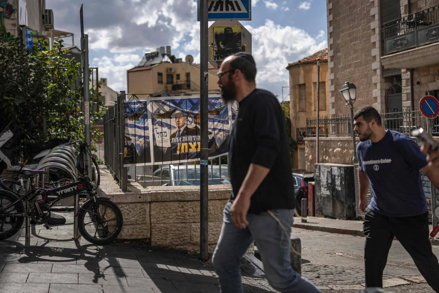 إسرائيليون يسيرون أمام ملصق لرئيس الوزراء الإسرائيلي بنيامين نتنياهو في القدس (أ.ف.ب)