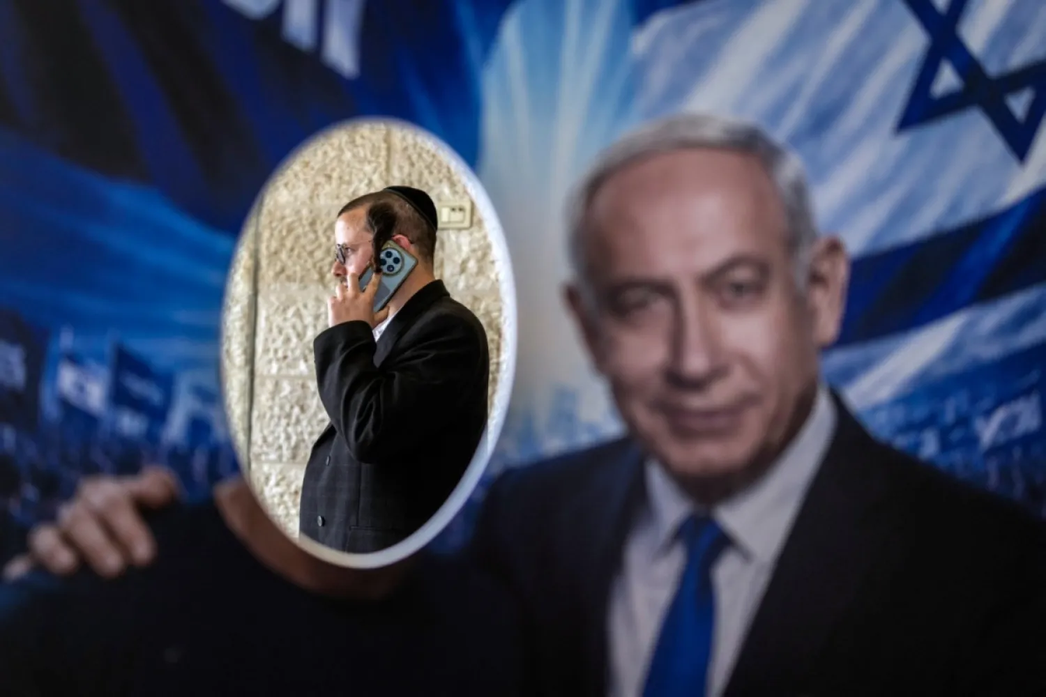Kudüs'te, İsrail seçimlerinden önce parti ön seçimleri sırasında bir seçim merkezinde, Likud partisi üyesi, İsrail Başbakanı Binyamin Netanyahu'ya ait bir posterin arkasında duruyor(AFP)