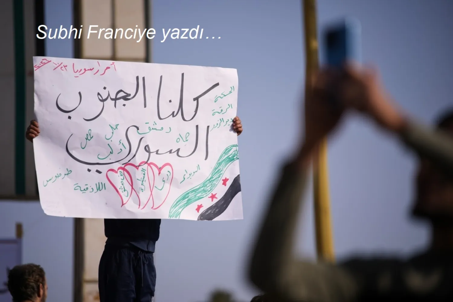 Suriye'nin Dera şehrinde, Kuneytra ve batı Dera bölgelerine yönelik İsrail askeri müdahalelerine karşı düzenlenen protestoda, bir gösterici Arapça olarak “Hepimiz Güney Suriye'yiz” yazılı pankart taşıyor, 23 Ekim 2026