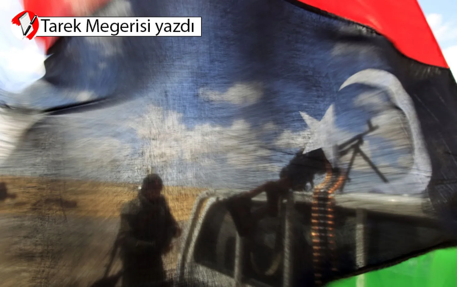 Ecdebiye şehrinin batı kapısında, cephe hattına yakın bir yerde, Libya Krallığı bayrağının arkasında muhalif güçlerden bir savaşçı(Reuters)