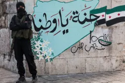 A member of the Syrian Salvation Government stands guard in front of a graffiti that reads "Heaven, my homeland" on New Year's Eve at the Bab Touma square, after the ousting of Syria's Bashar al-Assad, in Damascus, Syria, December 31, 2024. (Reuters) 