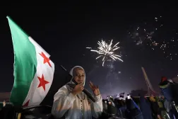 A young woman holds the Flag of Syria as people celebrate the New Year near Umayyad Square in Damascus, Syria, on January 1, 2025. (AFP)