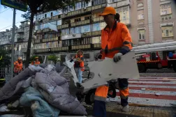 Workers clear debris and rubble from the street following a major overnight Russian attack in Kyiv on July 10, 2025, amid the Russian invasion of Ukraine. (Photo by OLEKSII FILIPPOV / AFP)