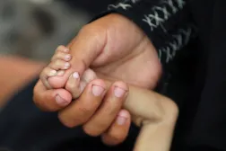 Palestinian mother Amira Muteir holds the hand of her five-month-old baby Ammar, whom she says is wasting away from malnutrition, in Gaza City, August 5, 2025. REUTERS/Mahmoud Issa    