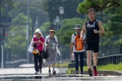 A man runs in the hot sun on a sidewalk near the Imperial Palace in Tokyo on August 6, 2025. (Photo by Kazuhiro NOGI / AFP)