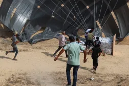 Palestinians run to collect food items as aid packages are dropped from an airplane, in Deir Al-Balah, in the central Gaza Strip August 12, 2025. (Reuters)