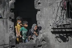 أطفال فلسطينيون ينظرون يوم الأربعاء من منزل عائلتهم المدمر إثر غارة جوية إسرائيلية استهدفت مخيم الشاطئ للاجئين بمدينة غزة (إ.ب.أ)