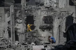 İsrail'in dün Gazze'nin batısındaki eş-Şati Mülteci Kampı’na düzenlediği hava saldırısının ardından yıkılan binaların enkazı arasında duran Filistinliler (EPA)