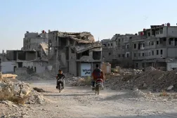 أشخاص يركبون دراجاتهم النارية أمام مبان مدمرة في داريا على مشارف دمشق في 28 أكتوبر 2025 (أ.ف.ب)