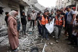 Gazze şehrinde İsrail hava saldırıları sonucu yıkılan bir evin enkazından çıkardıkları cesetleri taşıyan Filistinliler (AFP)