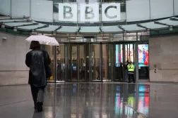 A person walks with an umbrella outside BBC Broadcasting House, after Director General Tim Davie and CEO of BBC News Deborah Turness resigned on Sunday, November 9, following accusations of bias at the British broadcaster, including in the way it edited a speech by US President Donald Trump, in London, Britain, November 14, 2025. REUTERS/Isabel Infantes
