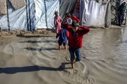 15 November 2025, Palestinian Territories, Khan Yunis: Children walk through the rainwater between their tents, as Palestinians suffer from the bitter cold and heavy rains that inundate their tents in the Al-Attar area of Mawasi, west of Khan Younis in the southern Gaza Strip. (dpa) 