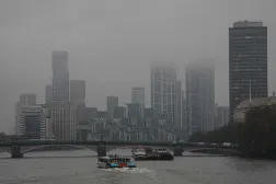  A catamaran (C) makes it way down the Thames towards high-rise buildings partly obscured by clouds in London on November 14, 2025, as inclement weather affects much of the country due to Storm Claudia. (AFP) 