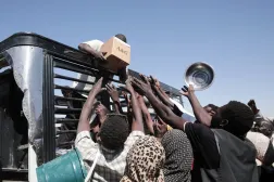 Sudanese families displaced from El-Fasher reach out as aid workers distribute food supplies at the newly established El-Afadh camp in Al Dabbah, in Sudan's Northern State, Sunday, Nov. 16, 2025. (AP Photo/Marwan Ali)