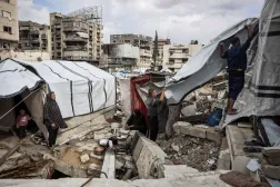 Gazze şehrindeki yerinden edilmiş kişiler için kurulan kampta kışın ilk yağmurları yağarken çadırlarını kurmaya çalışan Filistinliler (AFP)