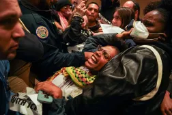 ضباط شرطة نيو أورلينز يحملون رجلاً خارج مبنى البلدية بعد مشاركته في احتجاج على نشر عملاء فيدراليين في المدينة (أ.ف.ب)