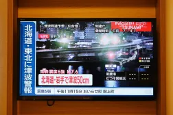 A tsunami warning flashes over live footage of a waterfront area, on a television screen in Sapporo, in Japan's northern Hokkaido prefecture on December 9, 2025. (AFP)