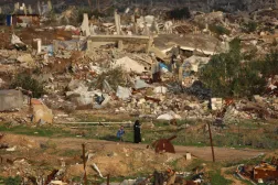 امرأة فلسطينية تمر عبر الدمار الناتج عن الحرب في مخيم النصيرات بوسط قطاع غزة (أ.ف.ب)