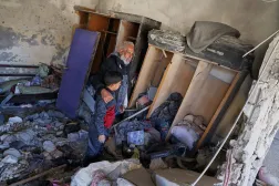Qassim Hamadeh, who lost two sons, a daughter-in-law, and his 4- and 10-year-old grandsons, among 13 villagers killed when Israeli troops raided Beit Jin, southwestern Syria, on Nov. 2, looks at the damage from the raid alongside one surviving grandson, Dec. 1, 2025. (AP Photo/Omar Albam) 