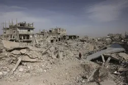 Gazze Şeridi'nin güneyindeki yıkılmış binaların enkazı arasında yürüyen Filistinli bir adam (AFP)