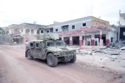 آلية للجيش اللبناني في بلدة ميس الجبل بجنوب لبنان تعبر قرب أبنية متضررة جراء الحرب (أرشيفية - رويترز)