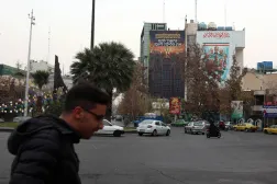 إيرانيون يمرون بجانب لوحة دعائية مناهِضة لإسرائيل تحمل عبارة: «نحن مستعدون. هل أنتم مستعدون؟» معلقة في ساحة فلسطين وسط طهران (إ.ب.أ)