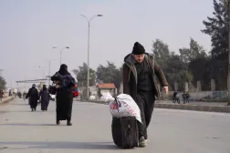 أشخاص مع أمتعتهم يسيرون على طول الطريق بعد أن اتفقت الحكومة السورية و«قوات سوريا الديمقراطية» على خفض التصعيد في مدينة حلب (رويترز)