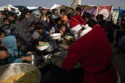 رجل بزي «سانتا كلوز» يشارك في مبادرة خيرية لتوزيع وجبات طعام لنازحين فلسطينيين بخان يونس الجمعة (إ.ب.أ)