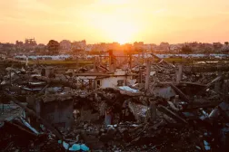 The sun sets behind the ruins of destroyed buildings in the Nuseirat refugee camp in the central Gaza Strip on December 31, 2025. (AFP)