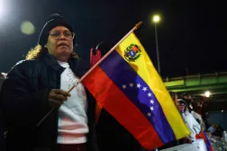 People hold the Venezuelan flag as they celebrate outside the Metropolitan Detention facility in the Brooklyn borough of New York, where ousted president Nicolas Maduro is expected to be held, on January 3, 2026 in New York City.  (Photo by John Lamparski / AFP)
