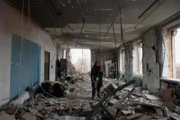 Kiev'de yıkılmış bir evin ortasında duran kadın (AFP)