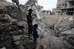 أطفال فلسطينيون يقفون بالقرب من حفرة في مخيم البريج وسط قطاع غزة (أ.ف.ب)