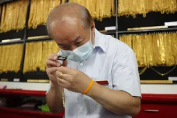 Bangkok'taki bir altın dükkanında altın takıları inceleyen bir kuyumcu (EPA)