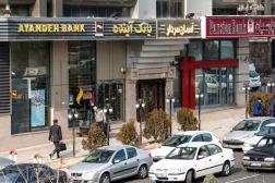 إيرانيون يمرون أمام أحد فروع بنك «آينده» عام 2017 (أ.ف.ب)