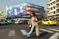 İranlı bir kadın, Tahran'ın merkezindeki Enghelab (Devrim) Meydanı'nda, devasa bir Amerikan karşıtı pankartın yakınından geçiyor (EPA)