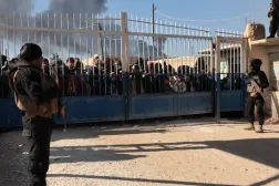 Suriye'nin kuzeydoğusunda DEAŞ üyelerinin ailelerinin kaldığı el-Hol Kampı’nın kapısının önünde duran Suriye güvenlik güçleri (EPA)