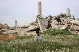 Perşembe günü Gazze Şeridi’nin orta kesiminde, Deyr el-Belah’ın kuzeyindeki Nusayrat Mülteci Kampı’nda, yıkılmış binaların yakınındaki bir tarladan çiçek toplayan Filistinli bir çocuk (AFP)