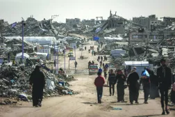 فلسطينيون يمشون وسط المباني المنهارة في مخيم جباليا للاجئين بشمال غزة (أ.ف.ب)