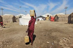 A displaced Sudanese woman carries plastic water containers at the Abu al-Naga displacement camp in the in Gedaref State, some 420km east of the capital Khartoum on February 6, 2026. (AFP)