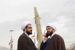 رجلا دين يشاركان في مراسم إحياء ذكرى الثورة بينما يعرض صاروخ باليستي في ميدان آزادي غرب طهران (رويترز)