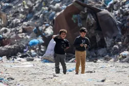 طفلان فلسطينيان يسيران قرب مكب نفايات في مدينة غزة يوم الأربعاء (رويترز)