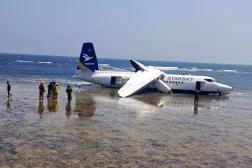 رجال الإنقاذ يقفون بالقرب من طائرة تحطمت على شاطئ البحر في مقديشو بالصومال (رويترز)