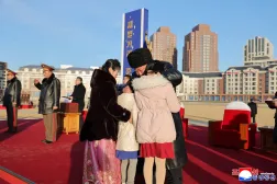 Kuzey Kore lideri Kim, Pyongyang'da yeni bir konut mahallesinin açılışında, savaşta hayatını kaybeden bir askerin aile üyelerine sarılırken (Reuters)