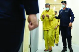 رجل أمن عراقي مع مشتبهين بالانتماء إلى «داعش» في سجن الكرخ ببغداد (أ.ب)