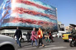 إيرانيون يسيرون بجوار لافتة دعائية ضخمة مناهضة للولايات المتحدة في أحد شوارع طهران الأربعاء (إ.ب.أ)