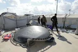 متعلقات سكان مخيم الهول خارج الخيم ويظهر أفراد من القوات الحكومية السورية بعد أن شهد فراراً جماعياً لأقارب مشتبه بانتمائهم لـ«داعش» (أ.ف.ب)