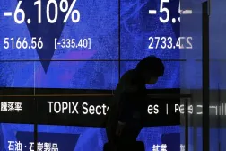 Tokyo’da borsa ekranının önünden geçen bir adam (EPA)